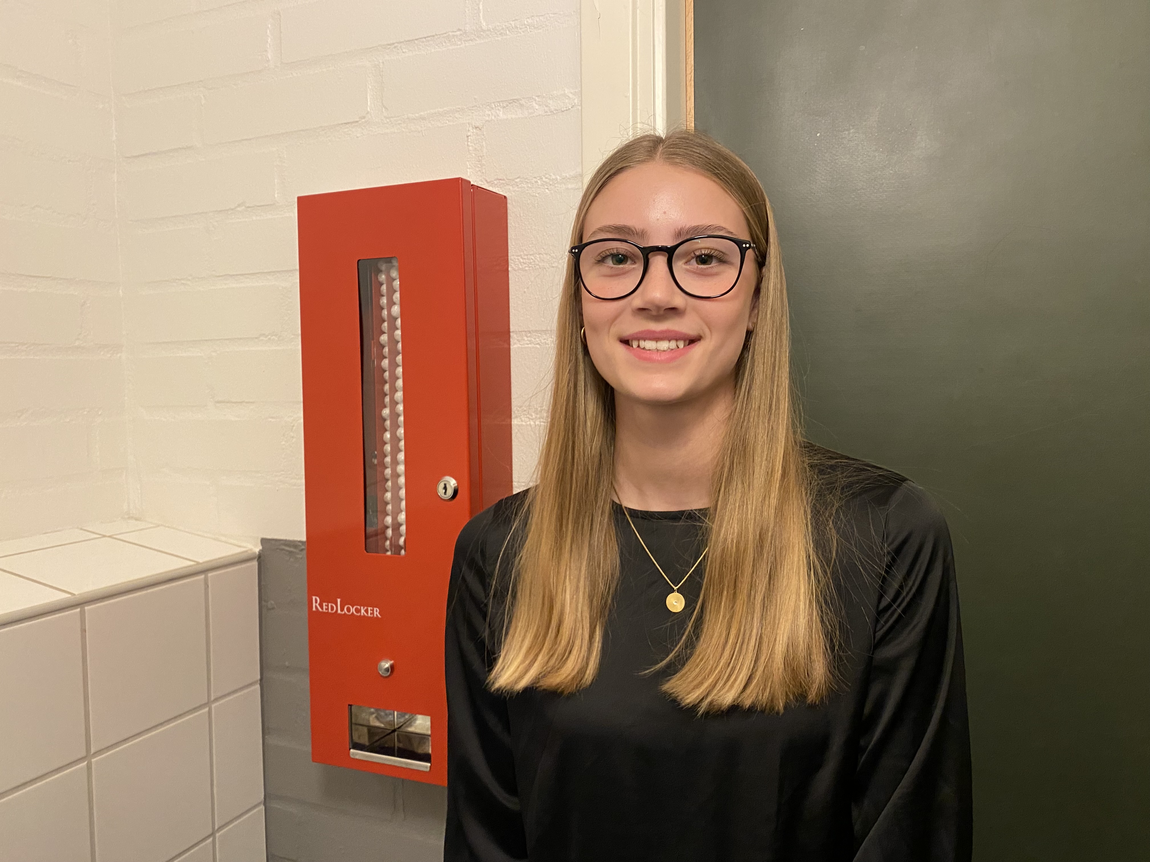 Elev står brevid en behållare med mensskydd på en skoltoalett..